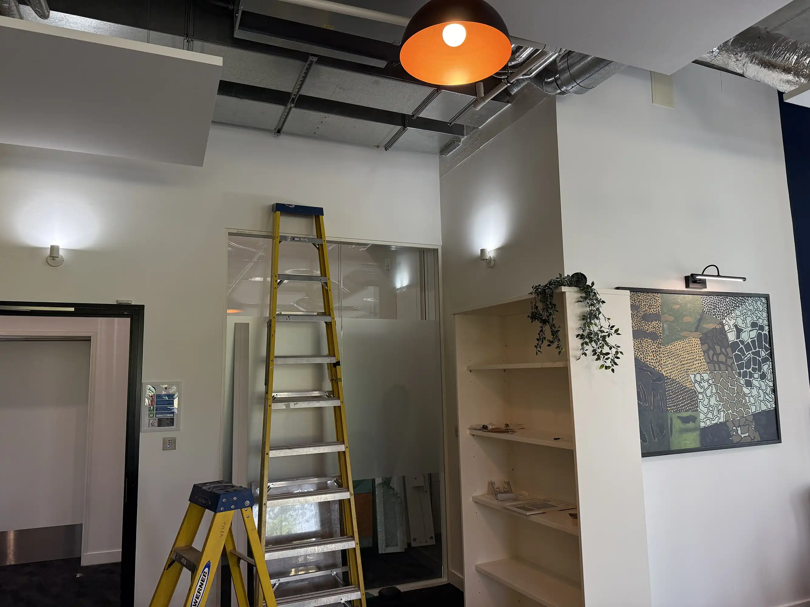 A room with a ladder and a painting on the wall.