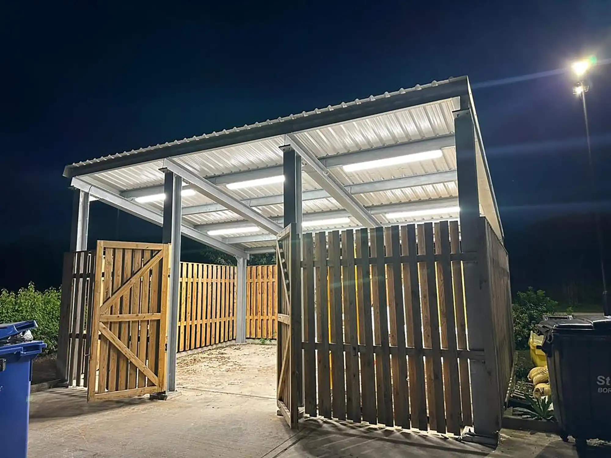 A metal shed with a wooden gate at night.