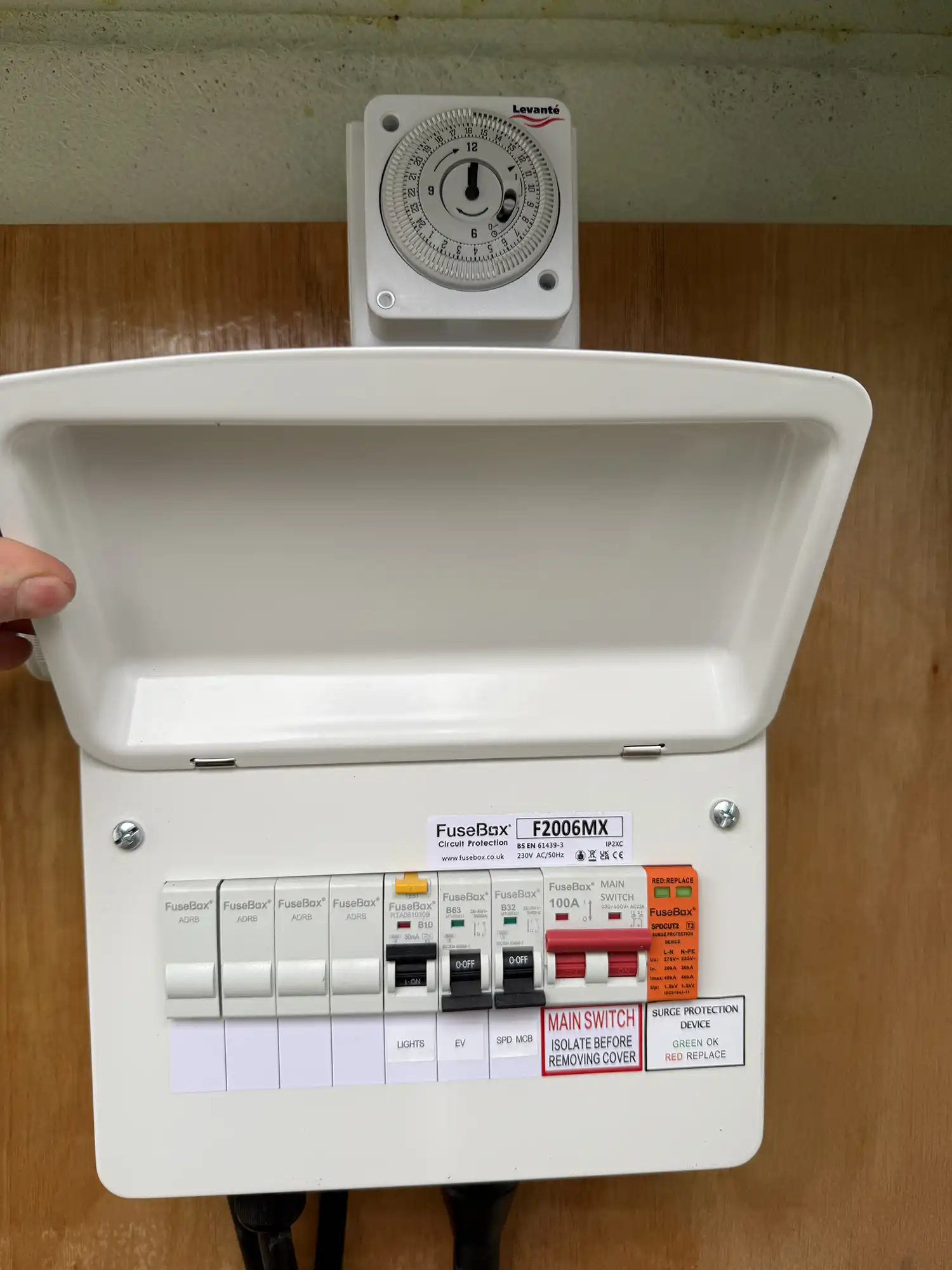 A person pointing at a switch box with a timer on top of it.