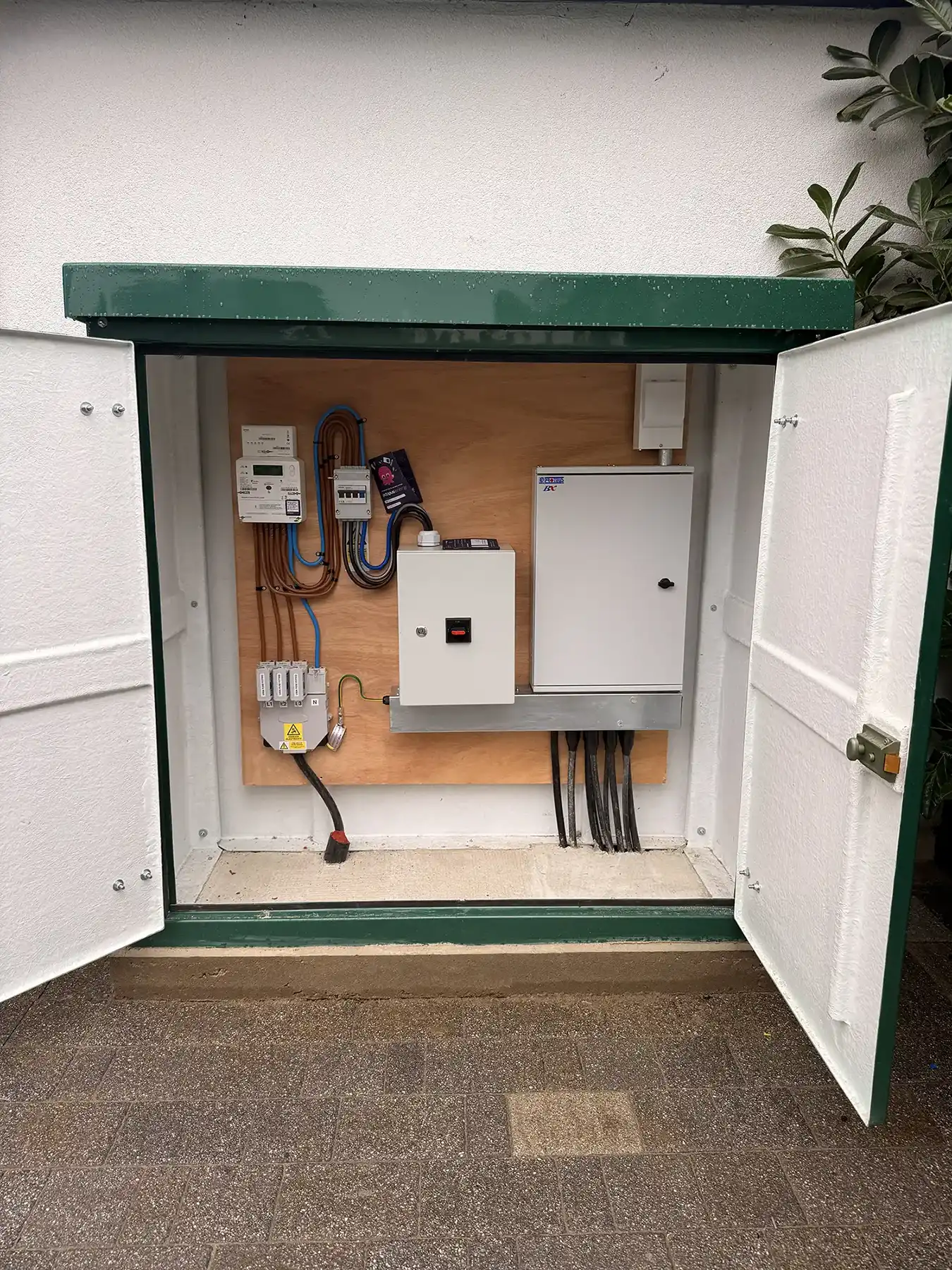 An electrical box is open on the side of a building.